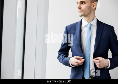 Porträt von ruhig junge Unternehmer auf der Suche durch das Fenster. Hellen Hintergrund. Stockfoto