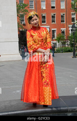 Eine schöne junge asiatische Frau posiert in einem traditionellen chinesischen Brautkleid im Washington Square Park in Greenwich Village, NYC Stockfoto