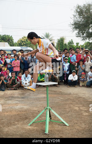 Eine Frau mit einem kleinen Fußball Kugel an der Spitze einer Glasflasche auf einer Plattform, Demoso, Kayah State in Myanmar zu jonglieren Stockfoto