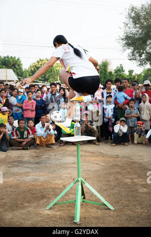 Eine Frau mit einem kleinen Fußball Kugel an der Spitze zwei Glasflaschen auf einer Plattform, Demoso, Kayah State in Myanmar zu jonglieren Stockfoto