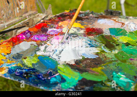 Leuchtend bunte Palette von blended Ölfarben mit einem professionellen Pinsel im Garten Stockfoto