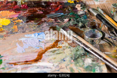 Nahaufnahme eines Malers Vorrichtungen oder Werkzeuge auf der hellen bunten Palette der blended Ölfarben Stockfoto