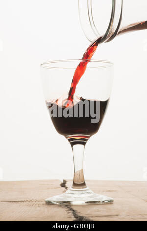 Ein Glas Rotwein aus einer Karaffe gefüllt werden Stockfoto