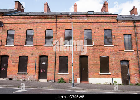 Eine lange Reihe von verlassenen Häusern in einer Straße mit Stahlplatten mit Brettern vernagelt. Stockfoto