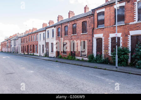 Eine lange Reihe von verlassenen Häusern in einer Straße mit Stahlplatten mit Brettern vernagelt. Stockfoto