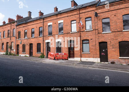 Eine lange Reihe von verlassenen Häusern in einer Straße mit Stahlplatten mit Brettern vernagelt. Stockfoto