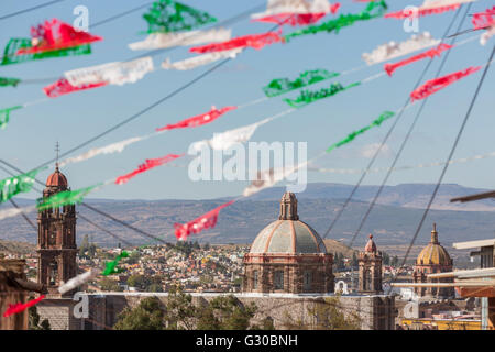 Festliche Papel Picado Banner schmücken eine Straße mit Blick auf die Kirche des Oratorio de San Felipe Neri im historischen Zentrum von San Miguel de Allende, Mexiko. Stockfoto