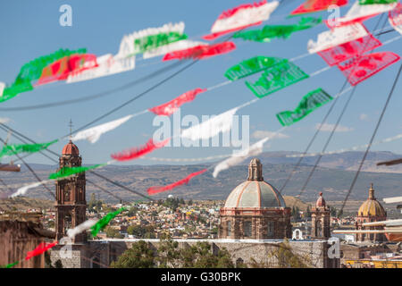 Festliche Papel Picado Banner schmücken eine Straße mit Blick auf die Kirche des Oratorio de San Felipe Neri im historischen Zentrum von San Miguel de Allende, Mexiko. Stockfoto