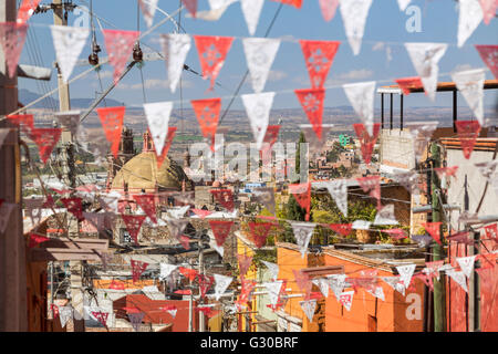 Festliche Papel Picado Banner schmücken eine Straße mit Blick auf die Kirche des Oratorio de San Felipe Neri im historischen Zentrum von San Miguel de Allende, Mexiko. Stockfoto