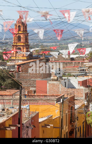 Festliche Papel Picado Banner schmücken eine Straße mit Blick auf die Kirche des Oratorio de San Felipe Neri im historischen Zentrum von San Miguel de Allende, Mexiko. Stockfoto