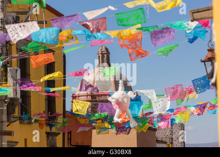 Festliche Papel Picado Banner schmücken eine Straße mit Blick auf die Kuppel des Oratorio de San Felipe Neri Kirche im historischen Zentrum von San Miguel de Allende, Mexiko. Stockfoto