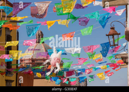 Festliche Papel Picado Banner schmücken eine Straße mit Blick auf die Kuppel des Oratorio de San Felipe Neri Kirche im historischen Zentrum von San Miguel de Allende, Mexiko. Stockfoto