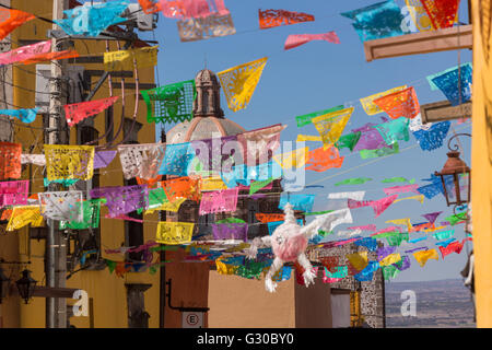 Festliche Papel Picado Banner schmücken eine Straße mit Blick auf die Kuppel des Oratorio de San Felipe Neri Kirche im historischen Zentrum von San Miguel de Allende, Mexiko. Stockfoto