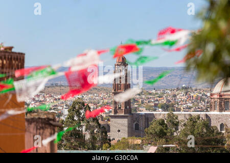 Festliche Papel Picado Banner schmücken eine Straße mit Blick auf die Kirche des Oratorio de San Felipe Neri im historischen Zentrum von San Miguel de Allende, Mexiko. Stockfoto