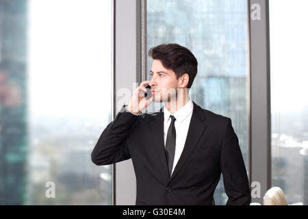 Geschäftsmann mit dem Handy arbeiten im Büro mit Blick auf Hochhäuser Stockfoto