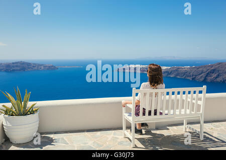 Junge Frau auf der Bank sitzen und auf dem Meer suchen Stockfoto
