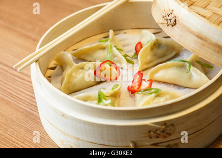 Dim-Sums - Wan Tan-mit Hühnerfleisch in einer Bambus-Box auf Holztisch im asiatischen Restaurant Stockfoto