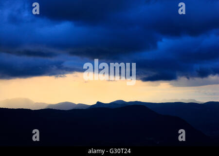 Gewitterhimmel über Hügel vor Sonnenuntergang Stockfoto