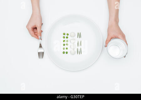 Draufsicht der jungen Frau Essen, grüne Erbsen, Mozzarella und Kräutern und wenn Sie mit Glas Wasser auf weißem Hintergrund Stockfoto