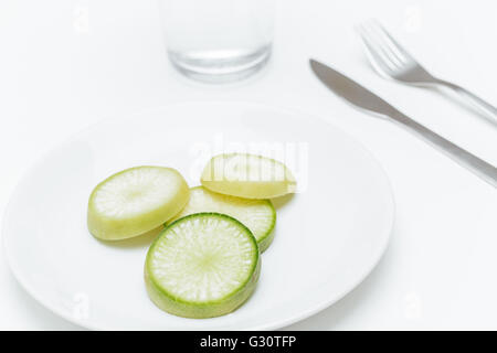 Teller mit grünen frischen Zucchini auf bedienten Tisch auf weißem Hintergrund Stockfoto