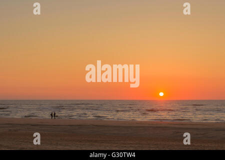 Ein feuriger Sonnenuntergang mit ein paar Hände am Strand von Katwijk Aan Zee, Südholland, Niederlande. Stockfoto