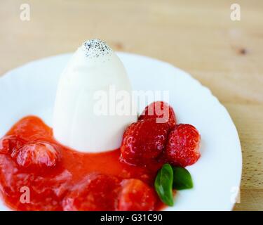 Panna Cotta mit Erdbeeren, Erdbeeren Sauce und Basilikum Blätter auf weißen Teller. Stockfoto