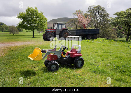 Traktor und Kinder-Spielzeug-Traktor auf Bauernhof bei Barbon, North Yorkshire, UK Stockfoto