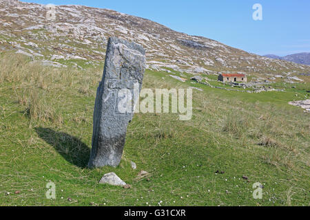 Standing Stone mit einem gravierten Kreuz auf z. Insel äußeren Hebriden mit einem Tierheim im Hintergrund Stockfoto