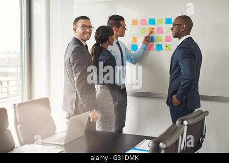 Fröhliche Gruppe von diversen Geschäftsleuten in Konferenz Meeting organisieren von Ideen auf große weiße Boa mit bunten Haftnotizen Stockfoto