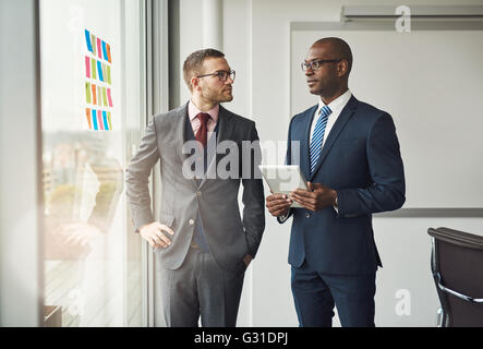 Zwei intelligente Business-Manager oder Co Büroangestellte in einem Diskussion steht vor einem Fenster mit bunten Memos auf dem Glas Stockfoto