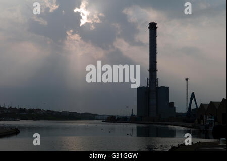 Sonne durch die Wolken über Fabrikschornsteinen Stockfoto