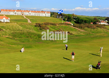 Golfer spielen auf dem fünften Grün den Ailsa Golfplatz von Trump Turnberry mit dem Hotel und Clubhaus im Hintergrund Stockfoto