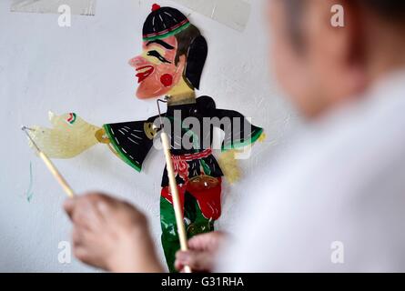 (160606)--TIANJIN, 6. Juni 2016 (Xinhua)--Schatten Marionette Künstler Zhang Kui spielt Schattenfiguren zu Hause in Tianjin, Nord-China, 5. Juni 2016. Zhang Kui, geboren 1937, ist jetzt eine Erbin der Schattenfiguren. Er hat hing von Schattenspielfiguren für 68 Jahre seit seiner Kindheit gelebt durchführen. "Mein Vater hatte 38 Schattenkästen, mein Bruder durchgeführt und ich schnitzte die Schattenfiguren," sagte der Erbe wenn er seiner Kindheit erinnert. Heute, wie wenige Leute die Schatten-Marionette-Leistung. Zhang Kui hatte einmal zwei Lehrlinge, aber beide schließlich aufgab und anderen prof durchgeführt Stockfoto