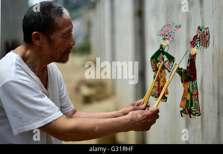 (160606)--TIANJIN, 6. Juni 2016 (Xinhua)--Schatten Marionette Künstler Zhang Kui führt ein Schattenspiel Marionette zu Hause in Tianjin, Nord-China, 5. Juni 2016. Zhang Kui, geboren 1937, ist jetzt eine Erbin der Schattenfiguren. Er hat hing von Schattenspielfiguren für 68 Jahre seit seiner Kindheit gelebt durchführen. "Mein Vater hatte 38 Schattenkästen, mein Bruder durchgeführt und ich schnitzte die Schattenfiguren," sagte der Erbe wenn er seiner Kindheit erinnert. Heute, wie wenige Leute die Schatten-Marionette-Leistung. Zhang Kui hatte einmal zwei Lehrlinge, aber beide schließlich aufgab und o durchgeführt Stockfoto