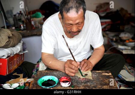 (160606)--TIANJIN, 6. Juni 2016 (Xinhua)--Schatten Marionette Künstler Zhang Kui Farben Schattenfiguren zu Hause in Tianjin, Nord-China, 5. Juni 2016. Zhang Kui, geboren 1937, ist jetzt eine Erbin der Schattenfiguren. Er hat hing von Schattenspielfiguren für 68 Jahre seit seiner Kindheit gelebt durchführen. "Mein Vater hatte 38 Schattenkästen, mein Bruder durchgeführt und ich schnitzte die Schattenfiguren," sagte der Erbe wenn er seiner Kindheit erinnert. Heute, wie wenige Leute die Schatten-Marionette-Leistung. Zhang Kui hatte einmal zwei Lehrlinge, aber beide schließlich aufgab und andere Pro durchgeführt Stockfoto