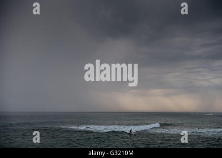 Aberystwyth Wales UK, Montag, 6. Juni 2016 UK Wetter: nach einem sehr warmen und feuchten Sommertag, dunkle Gewitterwolken mit Grollen des Donners, sammeln über eine Gruppe von Surfern im Meer vor Aberystwyth an der Cardigan Bay Küste von West Wales.   Temperaturen in vielen Teilen des Vereinigten Königreichs erreicht 25 º Celsius oder höher.   Bildnachweis: Keith Morris / Alamy Live News Stockfoto