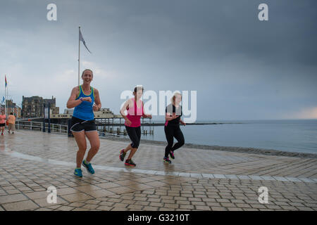 Aberystwyth Wales UK, Montag, 6. Juni 2016 UK Wetter: nach einem sehr warmen und feuchten Sommertag Frauen Joggen im Regen auf der Promenade wie dunkle Gewitterwolken mit Grollen des Donners, an der Cardigan Bay Küste von West Wales in Aberystwyth sammeln.   Temperaturen in vielen Teilen des Vereinigten Königreichs erreicht 25 º Celsius oder höher.   Bildnachweis: Keith Morris / Alamy Live News Stockfoto