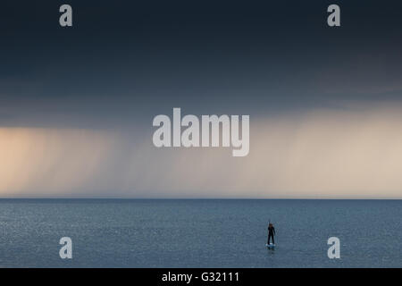 Aberystwyth Wales UK, Montag, 6. Juni 2016 UK Wetter: nach einem sehr warmen und feuchten Sommertag geht eine einsame Frau auf ihrem Stand up Paddle Board wie dunkle Gewitterwolken mit Grollen des Donners, Ther Meer in Aberystwyth an der Cardigan Bay Küste von West Wales sammeln.   Temperaturen in vielen Teilen des Vereinigten Königreichs erreicht 25 º Celsius oder höher.   Bildnachweis: Keith Morris / Alamy Live News Stockfoto