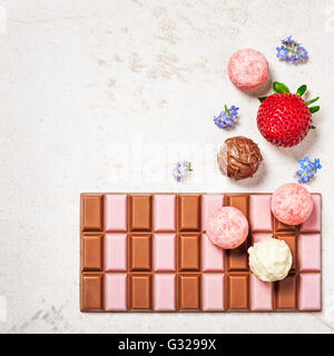 Erdbeere Schokolade Bar, Pralinen und Apple Blumen auf Stein Hintergrund. Köstliches Dessert. Ansicht von oben flach legen Stockfoto