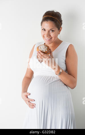 Schwangere Frau das Essen einer Cinnamon Roll Stockfoto