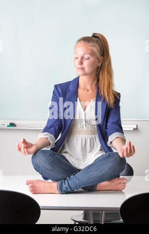 Geschäftsfrau sitzen barfuß in Yoga Position auf Ihrem Schreibtisch Stockfoto
