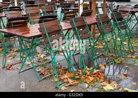 Leere Tische und Stühle für ein Restaurant im Freien bei Regen mit Herbstlaub in der historischen Innenstadt von Köln Stockfoto