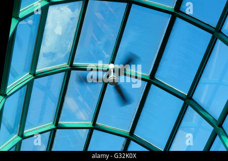 Spinnerei elektrischer Deckenventilator gegen ein Glas Dach und blauer Himmel Stockfoto