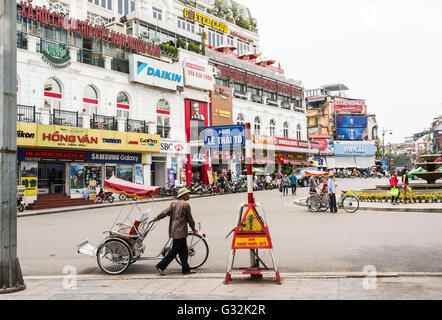 Mann mit Cyclo auf der Suche nach Touristen in einem der wichtigsten Plätze der alten Viertel von Hanoi. Stockfoto