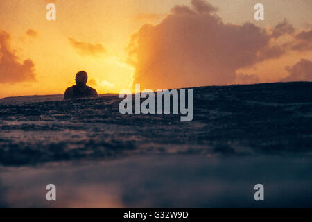 Silhouette des Surfers warten auf eine Welle im Regen zu fangen, Hawaii, Vereinigte Staaten Stockfoto