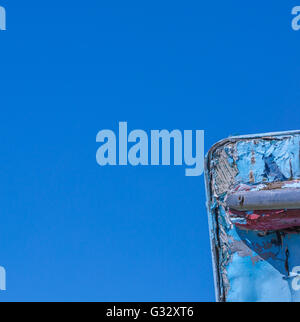 ein Detailbild von einem alten Holzboot mit abblätternde Farbe und Zeichen zu den Elementen ausgesetzt sein, jahrelang, strahlend blauer Himmel Stockfoto