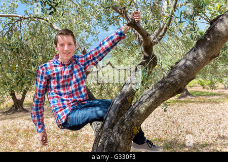 Europäische Teenager sitzen und hängen im Olivenbaum Stockfoto