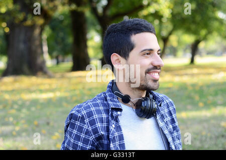 Nahaufnahme eines schönen jungen Mann mit Kopfhörern in einem Park. Im Freien. Stockfoto