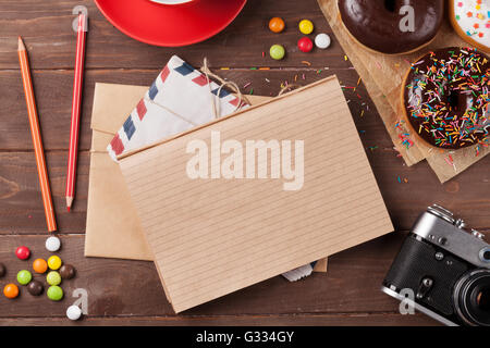 Notizblock, Donuts und Kaffee auf Holztisch. Draufsicht mit Textfreiraum Stockfoto