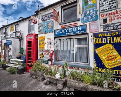 Gebäude mit Zinn Werbeschilder, darunter eine K6 Telefonzelle in Horseleap, County Offaly, Südirland bedeckt. Stockfoto